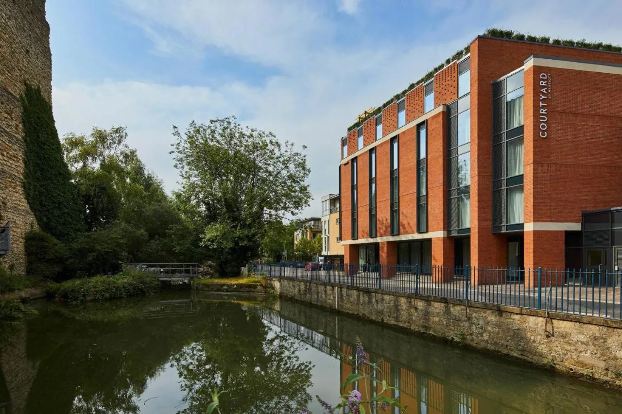 a building next to a river in front of a building at Courtyard by Marriott Oxford City Centre in Oxford